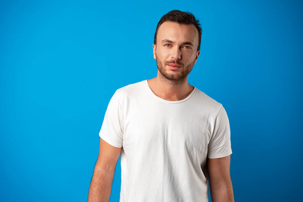 Portrait of smiling handsome guy in white t-shirt over blue background - Фото, зображення