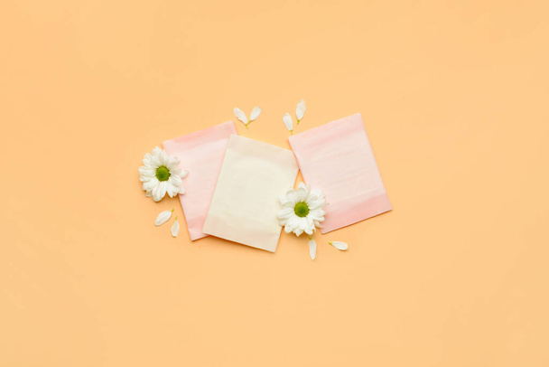 Flowers and menstrual pads on color background - Fotó, kép