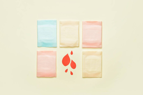Menstruační podložky a papírové kapky krve na světlém pozadí - Fotografie, Obrázek