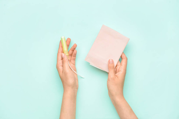 Female hands with menstrual pad and tampon on color background - Foto, imagen