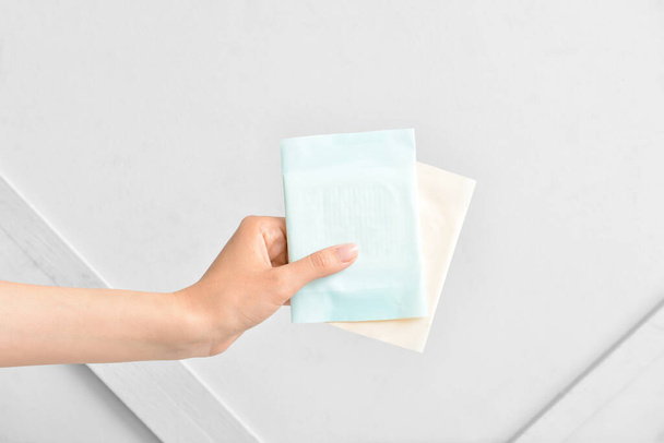 Weibliche Hand mit Menstruationspolstern auf hellem Hintergrund - Foto, Bild
