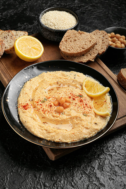 Plate finom hummus, kenyér és citrom sötét alapon - Fotó, kép