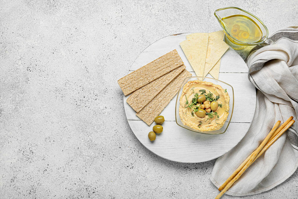 Ciotola con delizioso hummus, cracker e olive su sfondo chiaro - Foto, immagini