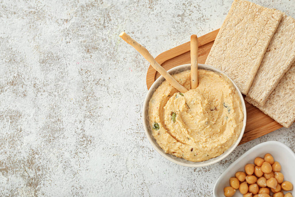 Bowl with delicious hummus and crackers on light background - Foto, Bild