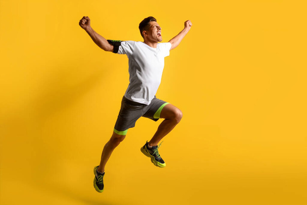 Sporty male runner on color background - Foto, imagen