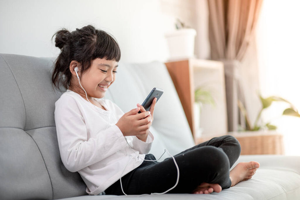 Little girl lying on the floor in the living room with tablet looking at device screen watching cartoons enjoy audiobook listening, preschool modern tech user parental control safety, - Photo, Image