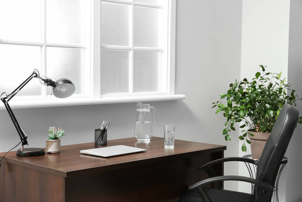 Moderní pracoviště s laptopem, džbánem a sklenicí vody v kanceláři - Fotografie, Obrázek