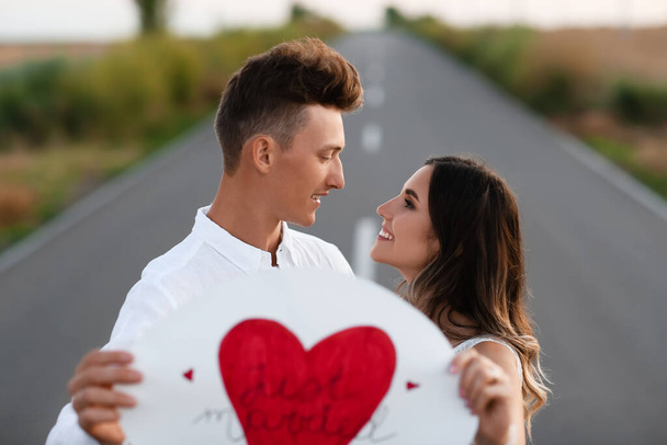 Ευτυχισμένο ζευγάρι γάμου με αφίσα στο δρόμο στην ύπαιθρο - Φωτογραφία, εικόνα