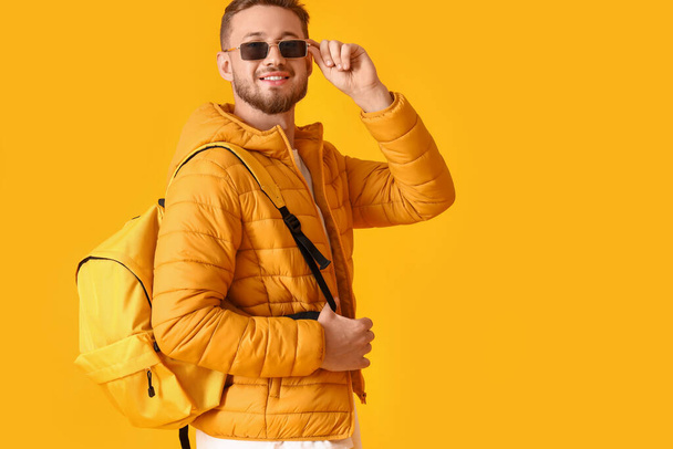 Stylish young man with sunglasses on yellow background - Foto, afbeelding