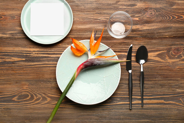 Tischdekoration mit schöner Paradiesvogel-Blume auf dunklem Holzhintergrund - Foto, Bild