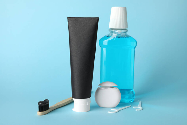Tube van zwarte tandpasta, borstel, spoel en floss op blauwe achtergrond - Foto, afbeelding