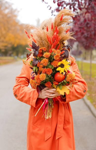 Joven mujer de moda sosteniendo ramo en el parque de otoño - Foto, Imagen