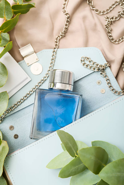 Lahvička parfému, stylová kabelka a eukalyptové větve na textilním pozadí - Fotografie, Obrázek
