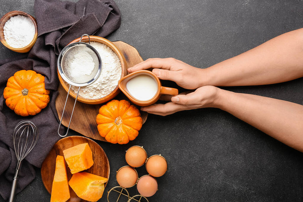 Female hands with fresh ingredients for preparing pumpkin pie on black background - Foto, Imagem