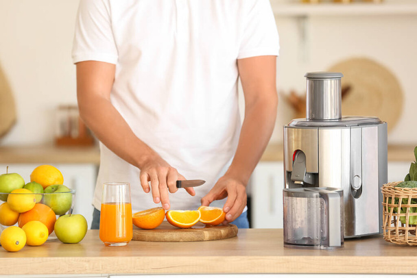 Young man preparing healthy fruit juice in kitchen - Photo, Image