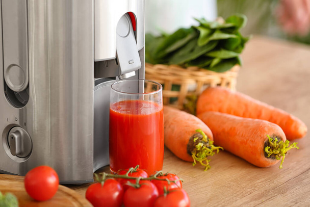 Сучасний соковижималка зі свіжими овочами і склянкою соку на столі на кухні
 - Фото, зображення