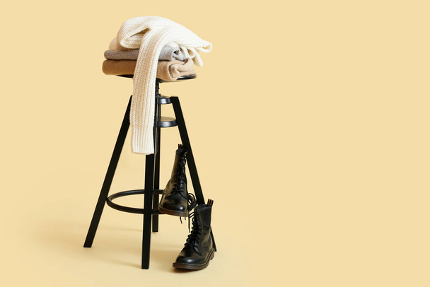 Stylish winter clothes on stool against color background - Photo, Image