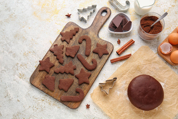 Wooden board with tasty chocolate Christmas cookies and dough on light background - Valokuva, kuva