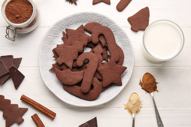Assiette avec de savoureux biscuits de Noël au chocolat et verre de lait sur fond de bois blanc - Photo, image