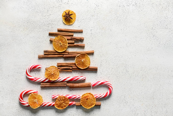Árbol de Navidad hecho de canela, bastones de caramelo y rodajas de cítricos secos sobre fondo claro - Foto, Imagen