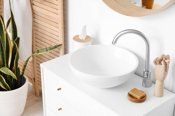 Modernes Waschbecken mit Seife, hölzerner Hand und Seidenschachtel in der Nähe der Lichtwand - Foto, Bild