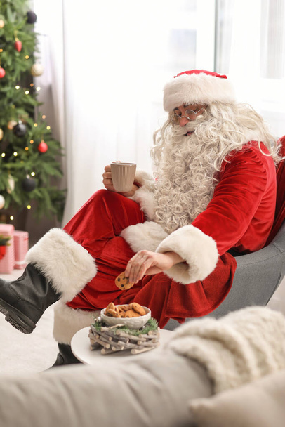 Święty Mikołaj je smaczne ciasteczka z herbatą w domu - Zdjęcie, obraz