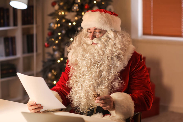 Santa Claus comiendo sabrosas galletas en casa por la noche - Foto, Imagen