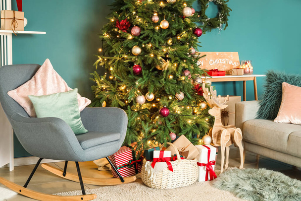 Interior of stylish living room with big Christmas tree, armchair and gift boxes - Foto, Bild