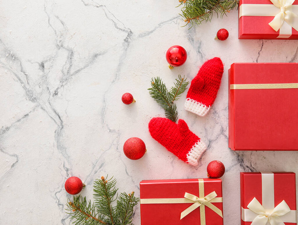 Noel hediye kutularıyla güzel kompozisyon, köknar dalları, beyaz mermer arka planda eldivenler ve toplar - Fotoğraf, Görsel