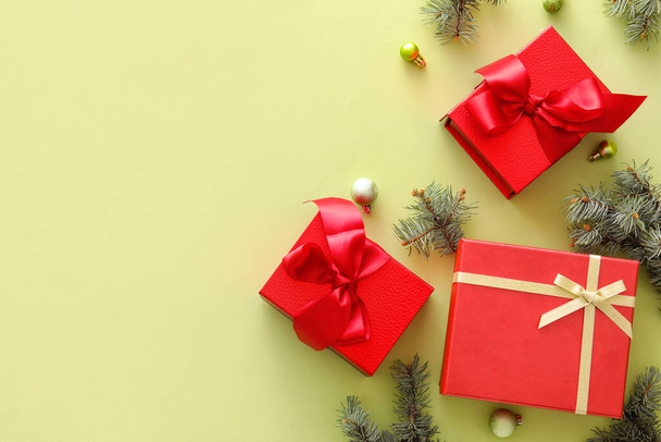 Красивая композиция с рождественскими подарочными коробками, еловыми ветвями и шариками на желтом фоне - Фото, изображение