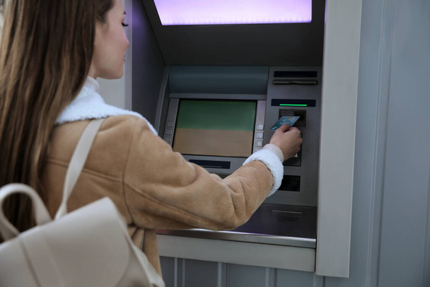 Young woman using cash machine for money withdrawal outdoors, focus on hand - Foto, Imagen