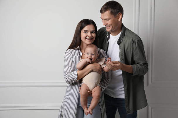 Happy family. Couple with their cute baby near light wall, space for text - Foto, Bild