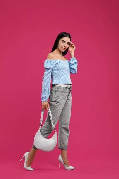 Fashionable young woman with stylish bag on pink background - Foto, afbeelding