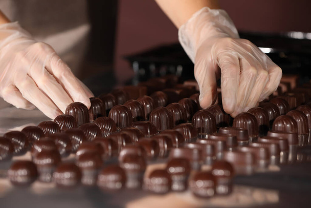 Woman with delicious candies at production line, closeup - Foto, afbeelding