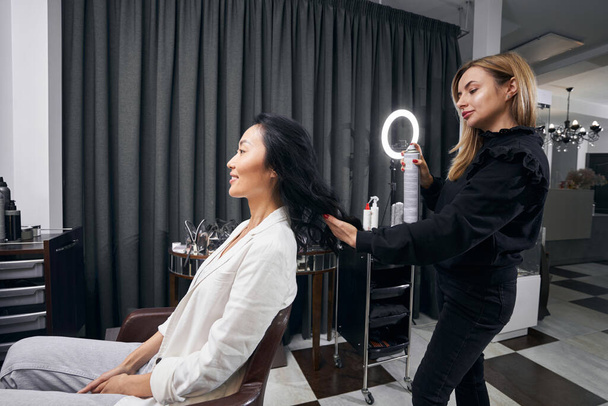 Charming pretty Asian female getting hair procedure at parlor - Фото, изображение