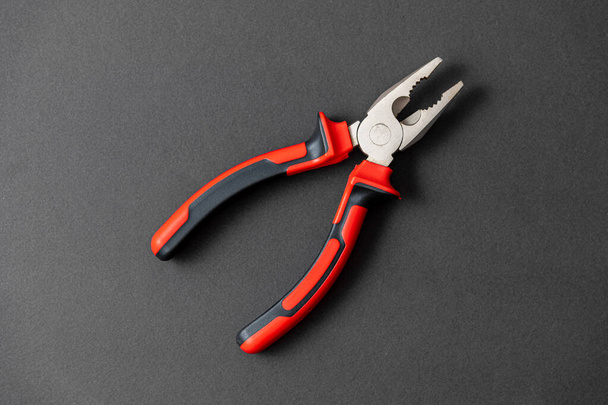 Pliers in red and black colored on a black background with blank text space - Foto, immagini
