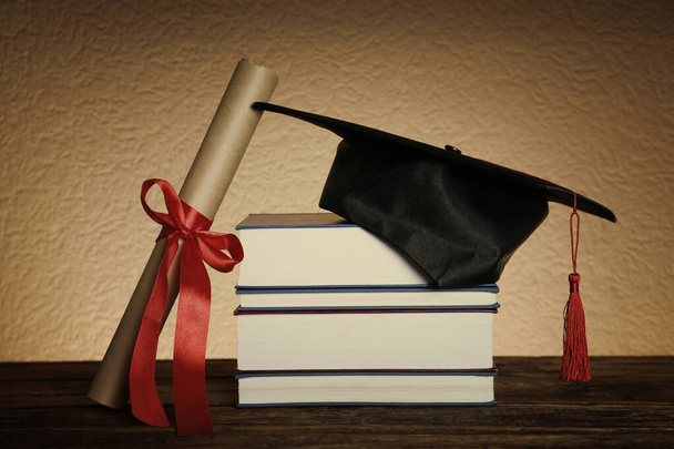 Graduation hat, books and diploma on wooden table - Φωτογραφία, εικόνα