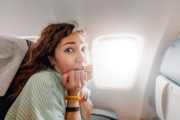 Vrouw met aerofobie is bang om in een vliegtuig te vliegen en ervaart een paniekaanval. Emoties van angst en angst bij de passagiers - Foto, afbeelding