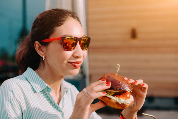 Happy asijské mladá žena jíst lahodné fastfood burger v ulici potravin restaurace - Fotografie, Obrázek