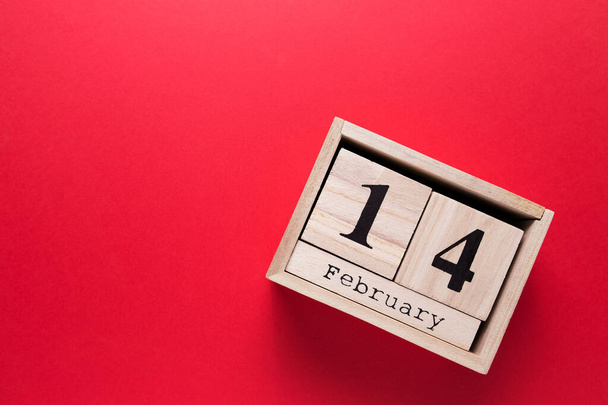 Wooden calendar with the inscription February 14 on a red isolated background - Foto, immagini