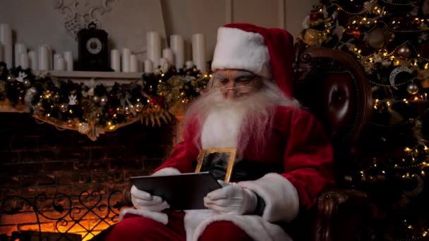 Moderni hymyilevä joulupukki pelaa mobiilipeliä tabletilla, uudenvuoden talvilomat - Materiaali, video
