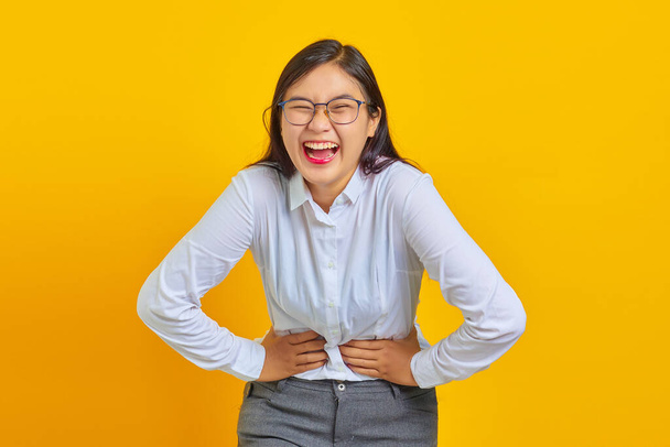 Portret van jonge zakenvrouw lachend van harte om grappige gekke grap met handen op het lichaam - Foto, afbeelding