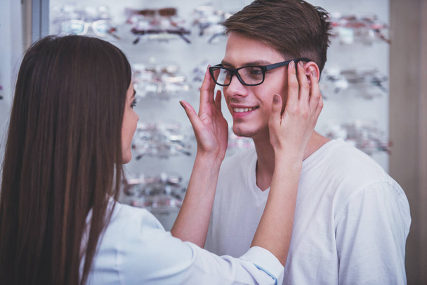 Optical store, client man and professional specialist help to choose. - Foto, Bild