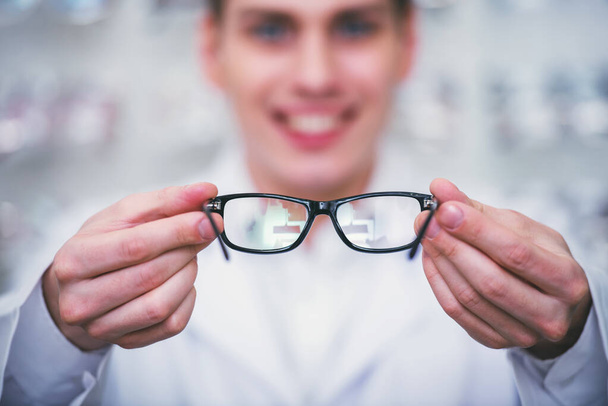 Optometrist está olhando para a câmera na loja de óculos. Jovem trabalhador profissional
. - Foto, Imagem