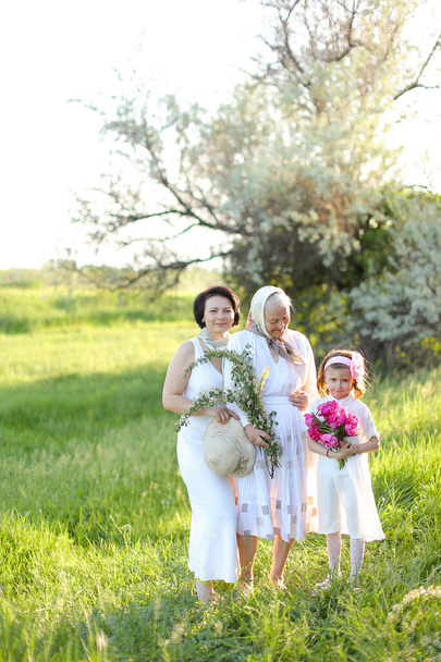 Europea vieja abuela en vestido blanco con hija y nieta fuera. - Foto, imagen