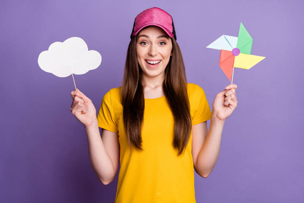 Photo of cheerful young happy positive woman wear cap hold hands stick clouds isolated on purple color background - Photo, image