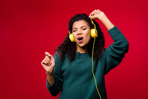 Photo of cheerful nice dark skin young funky woman dance wear headphones isolated on red color background - 写真・画像