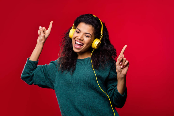 Photo of funny charming dark skin woman dressed green pullover headphones dancing singing isolated red color background - Foto, afbeelding
