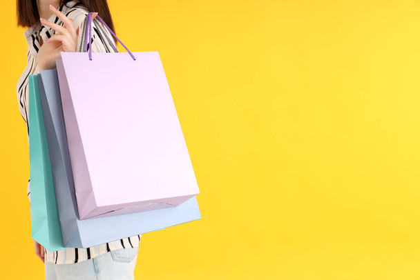 Frau hält Einkaufstaschen auf gelbem Hintergrund - Foto, Bild