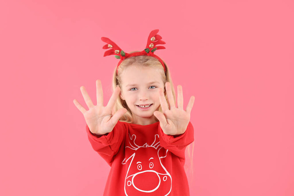 Маленька дівчинка в різдвяному одязі на рожевому тлі
 - Фото, зображення
